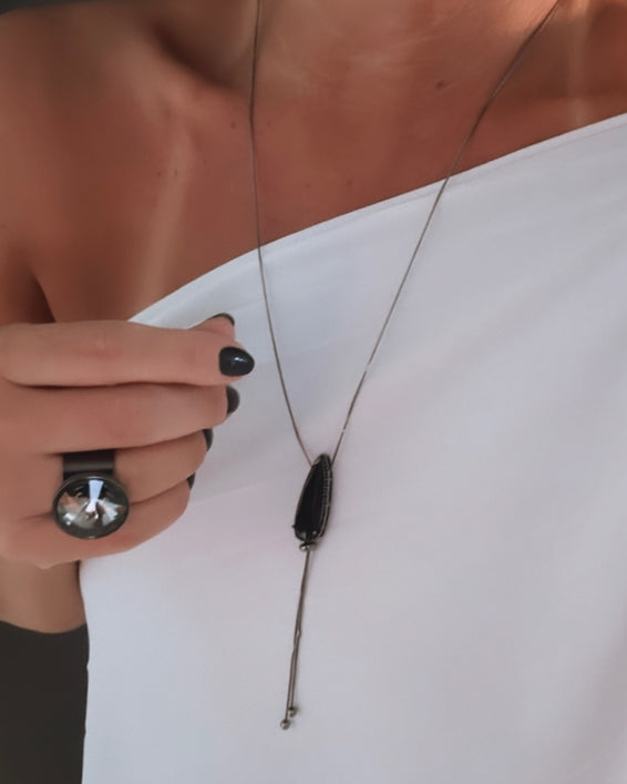 Colar de corrente fina com pingente escuro alongado e fecho discreto