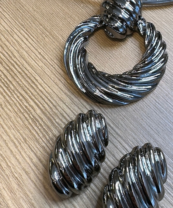 Par de brincos de argola metálicos ovalados, com textura ondulada e acabamento prateado