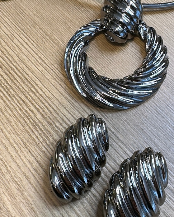 Par de brincos de argola metálicos ovalados, com textura ondulada e acabamento prateado