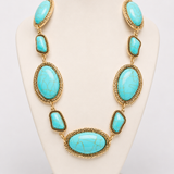Colar de pedras turquesa em formatos oval e gota com acabamento dourado, em colarinho.