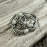Pulseira de argolas prateadas com contas brancas e pedras brilhantes