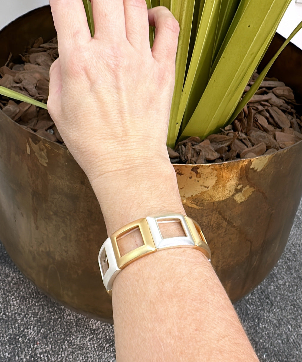 Pulseira dourada com inserções quadradas brancas e fecho lateral