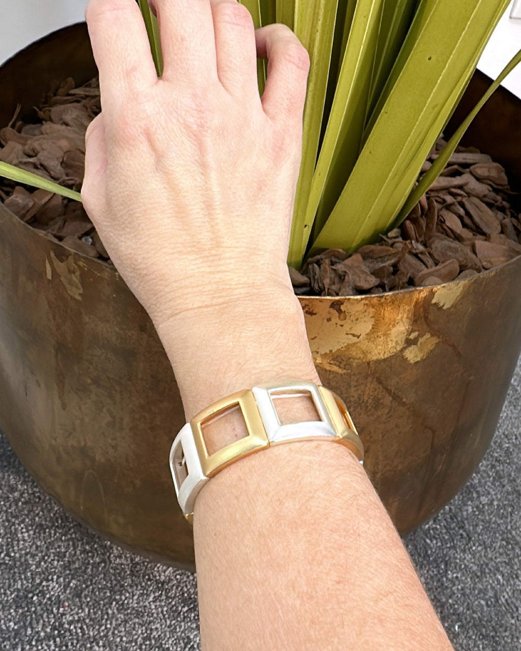 Pulseira dourada com inserções quadradas brancas e fecho lateral