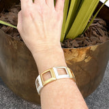 Pulseira dourada com inserções quadradas brancas e fecho lateral