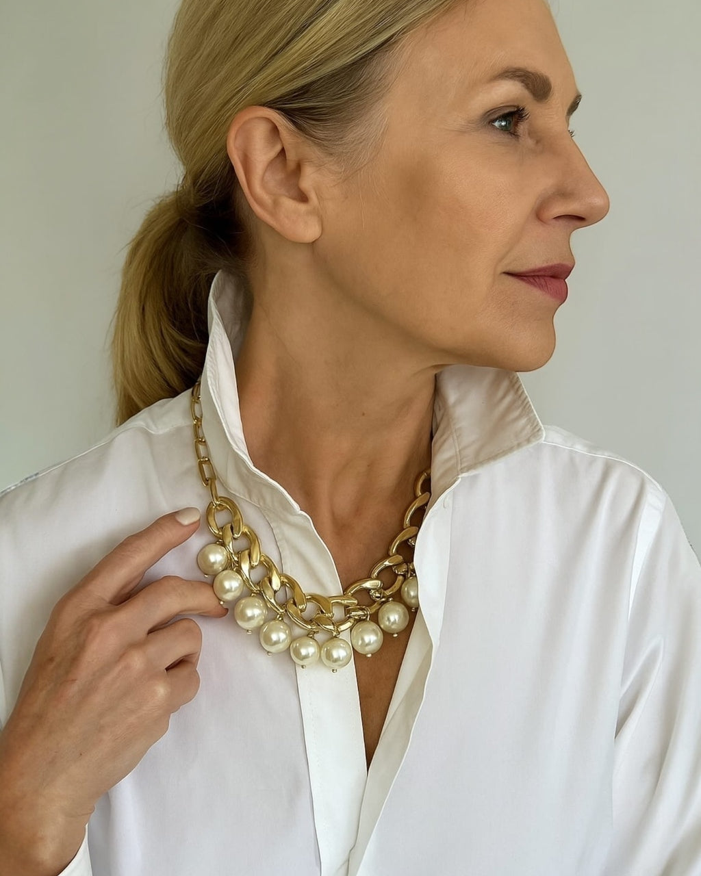 Colar dourado com correntes e pérolas brancas em camadas, fecho visível