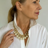Colar dourado com correntes e pérolas brancas em camadas, fecho visível