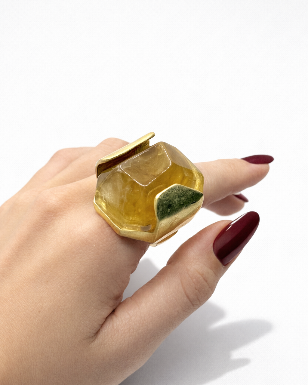Anel com pedra amarela e aro dourado, com detalhe verde no topo
