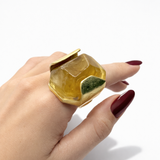 Anel com pedra amarela e aro dourado, com detalhe verde no topo