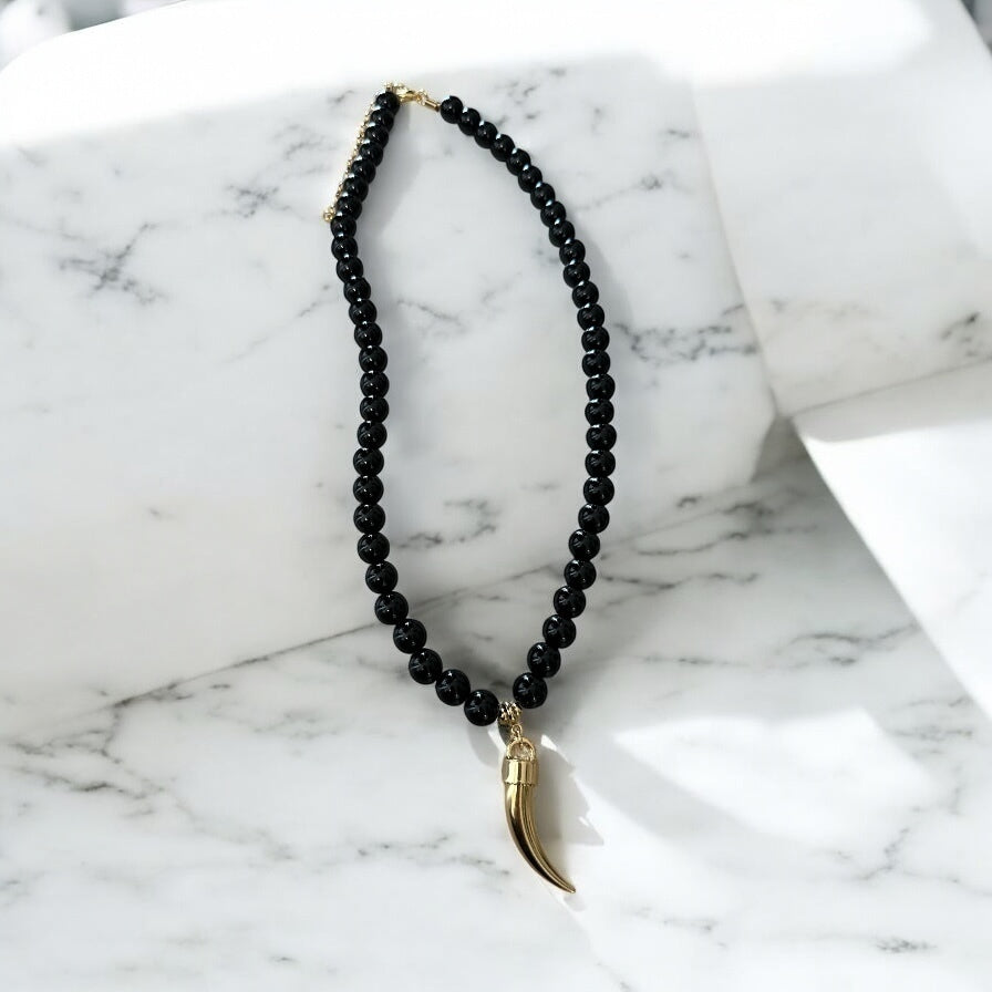 Colar de contas pretas com pingente de chifre dourado