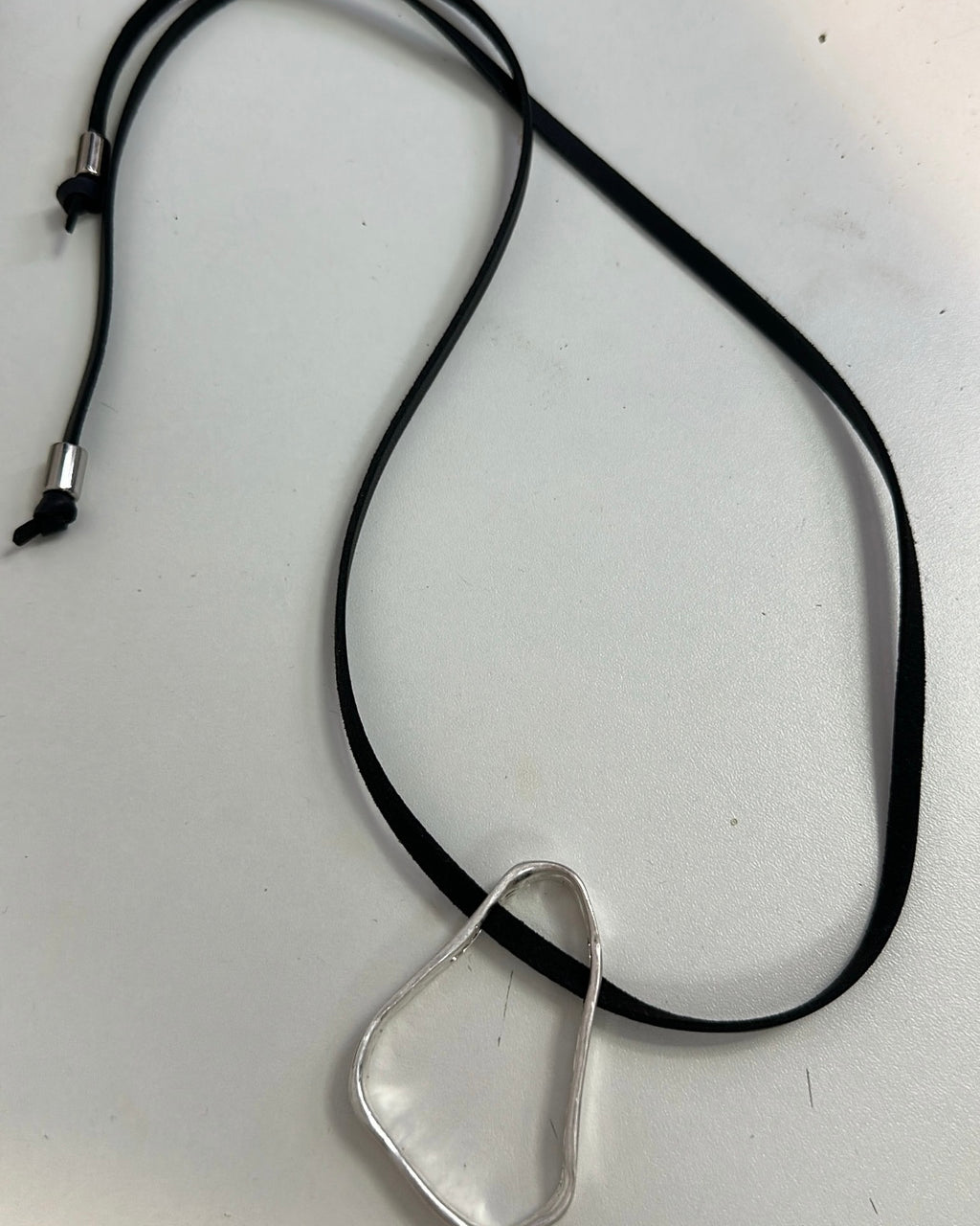 Colar com cordão preto e pingente prateado liso em formato de gota