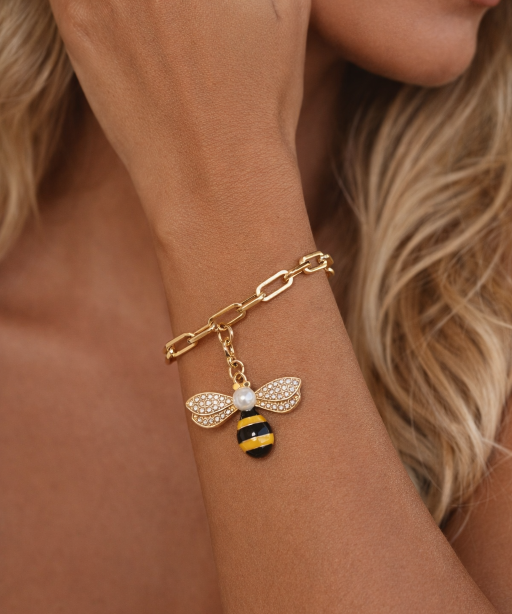 Pulseira em metal dourado com pingente de abelha e detalhes com zircônias
