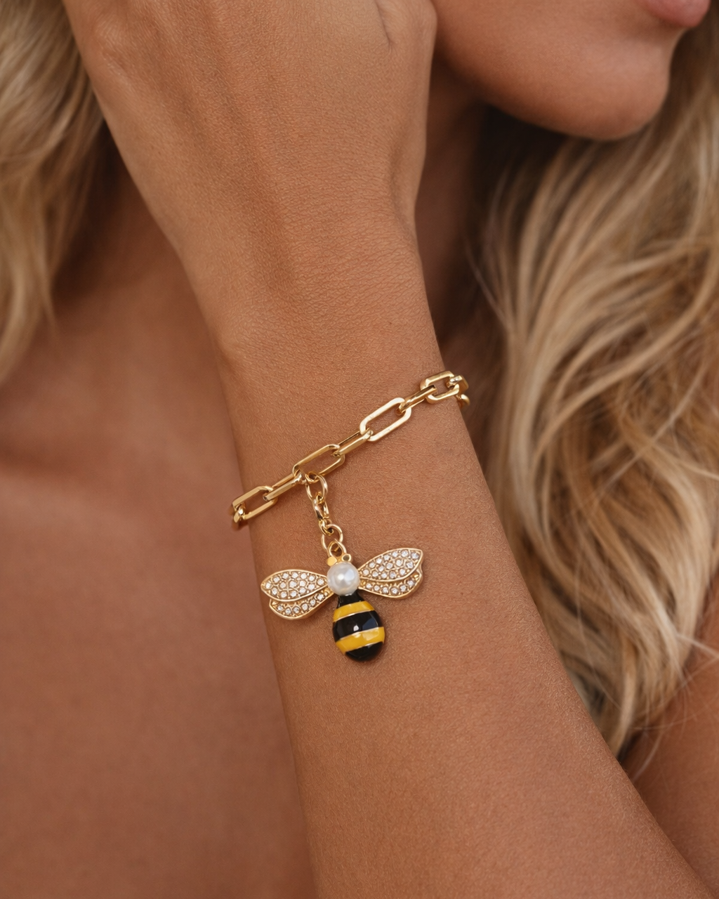Pulseira em metal dourado com pingente de abelha e detalhes com zircônias