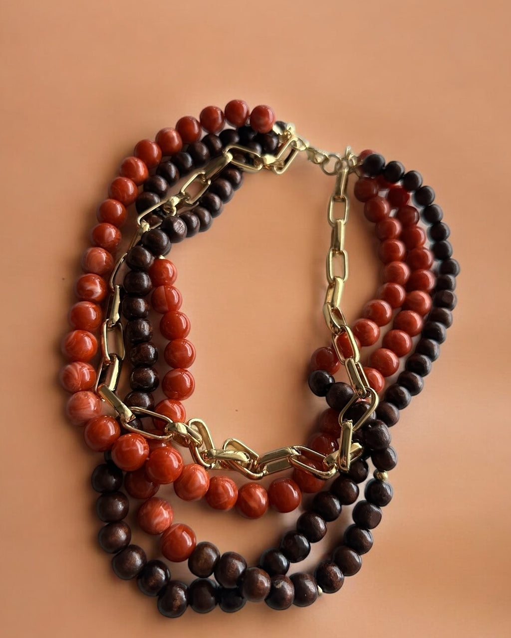 Colar maxi de contas em vermelho, marrom e preto, com argolas e fecho dourado