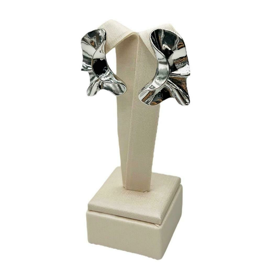 Par de brincos prateados com formato de flor e detalhes escuros