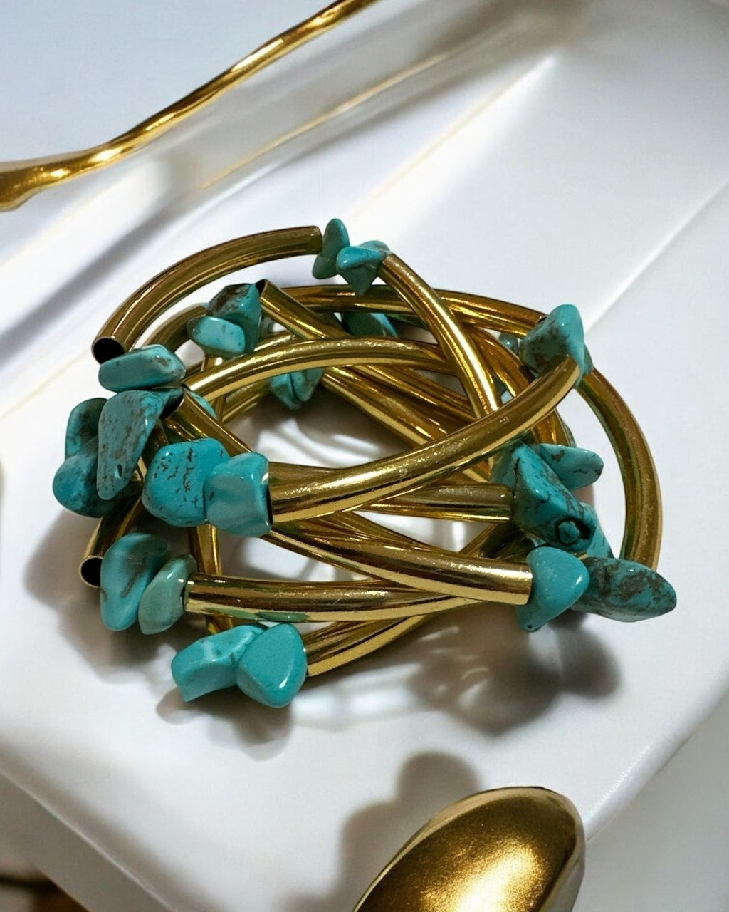 Pulseira dourada com pedras azul-turquesa em hastes trançadas