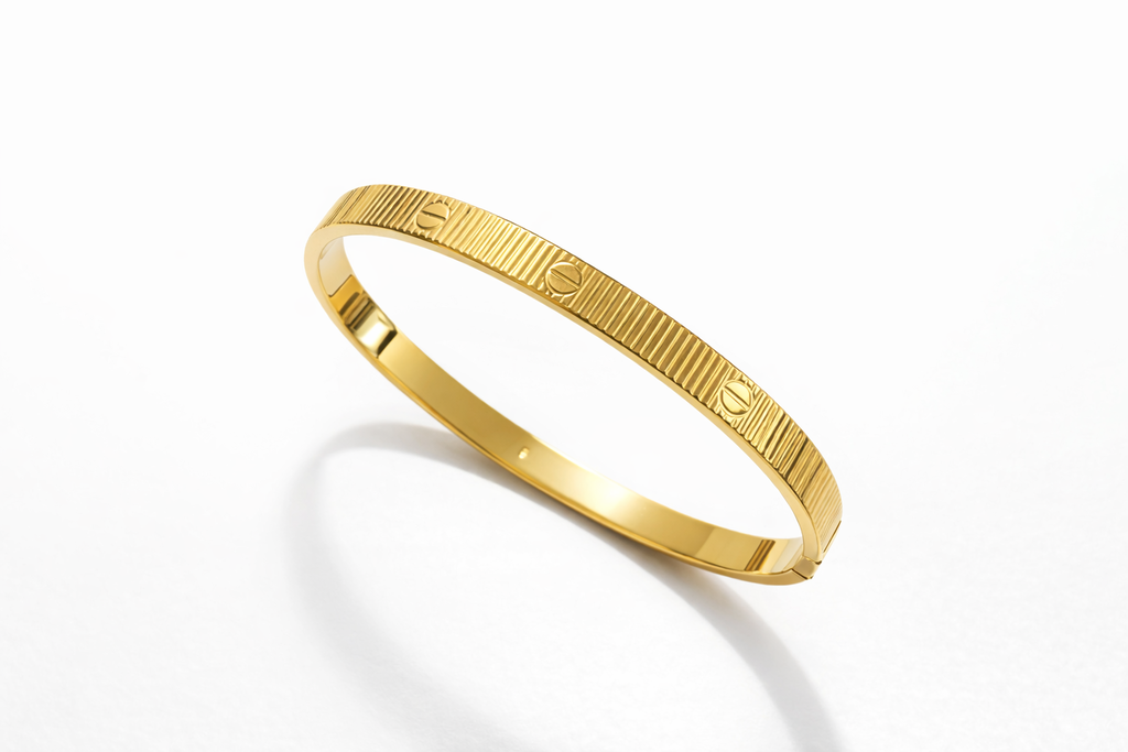Pulseira Carti de listras douradas, aro fino com padrão gravado e brilho metálico.
