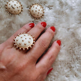 Brinco redondo dourado com base creme e tachas pontilhadas