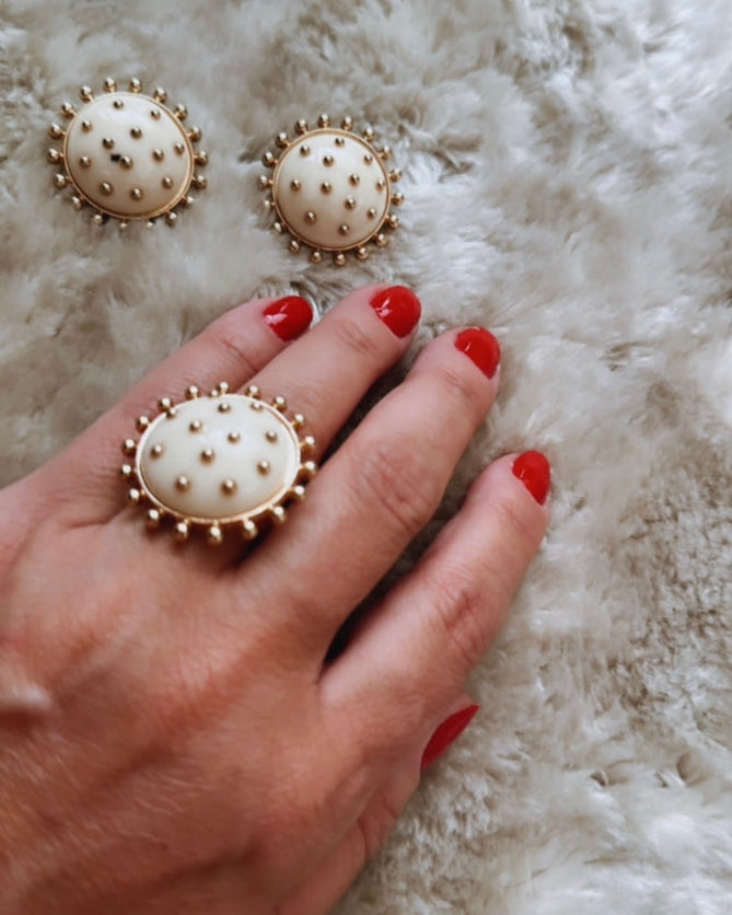 Brinco redondo dourado com base creme e tachas pontilhadas