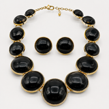 Conjunto de colar e brincos com pedras ovaladas pretas e acabamento dourado