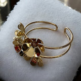 Pulseira dourada com argolas e pingentes florais com pedras coloridas