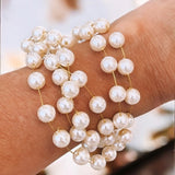 Pulseira dourada com pérolas mini e pingentes esféricos; fecho lagosta e extensor.