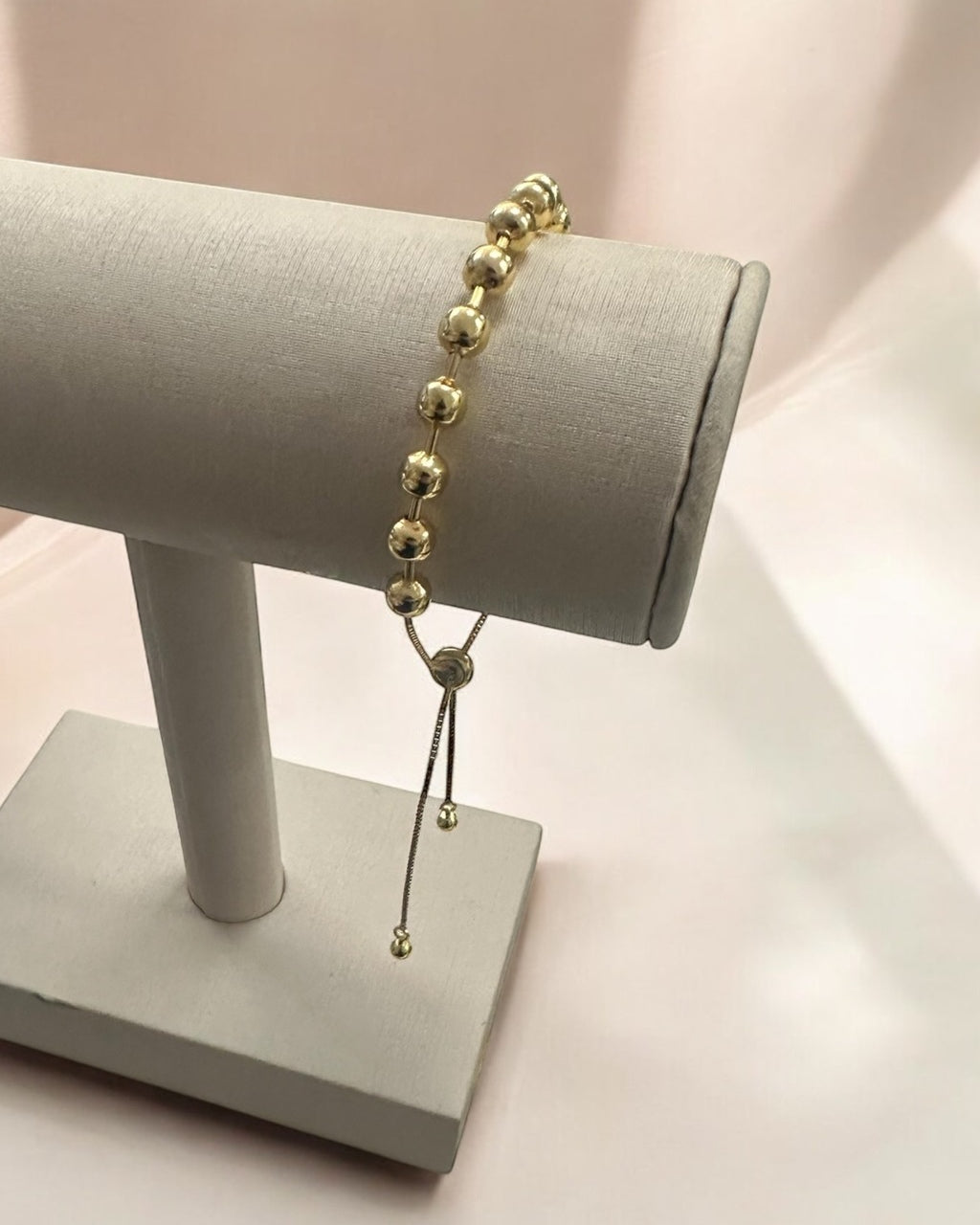 Pulseira Lia com contas douradas e pingente longo com detalhe de elos.
