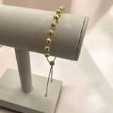 Pulseira Lia com contas douradas e pingente longo com detalhe de elos.