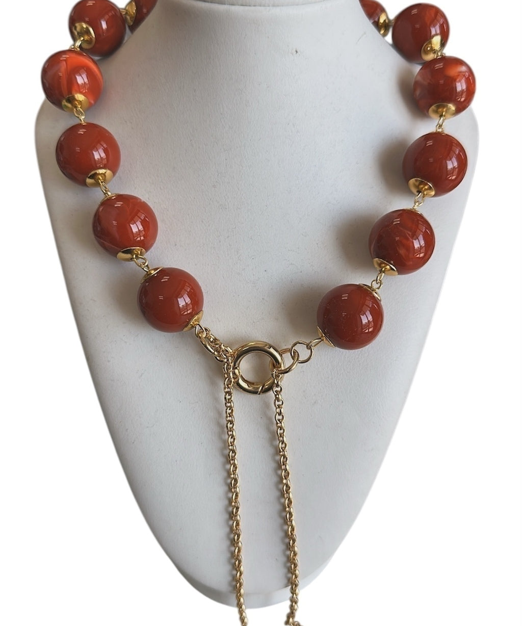 Colar com contas vermelhas e fecho dourado, com correntes pendentes