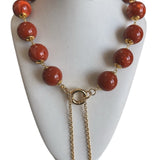 Colar com contas vermelhas e fecho dourado, com correntes pendentes