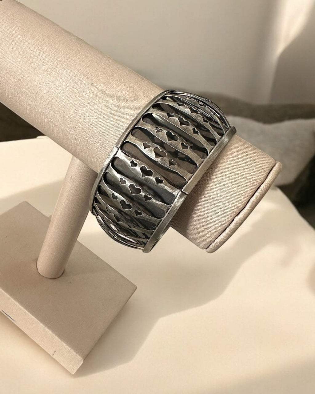 Bracelete metálico largo com padrão gravado em linhas e recortes, acabamento escuro