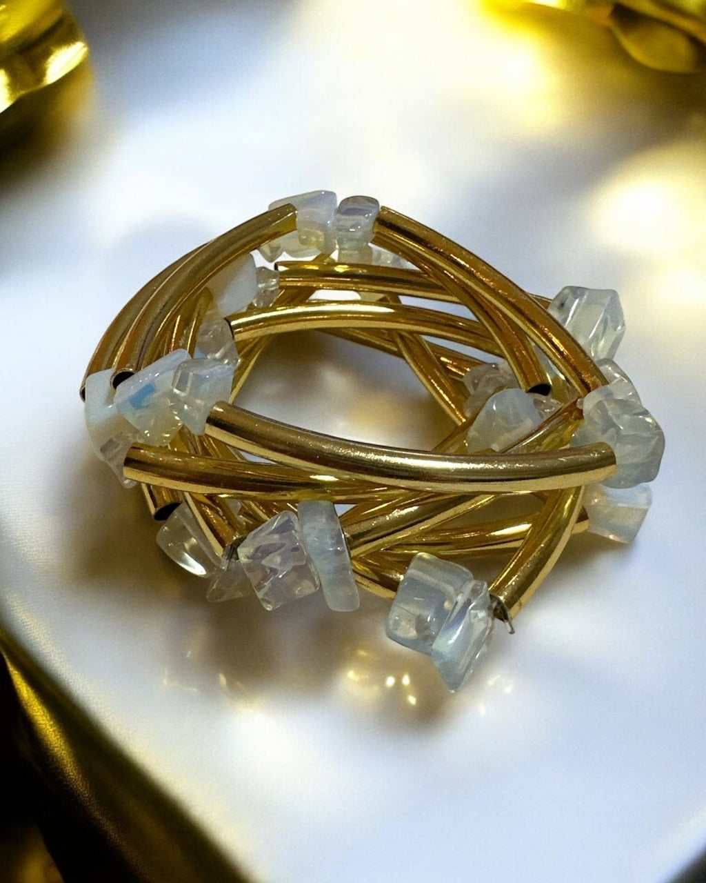 Pulseira dourada com pedras transparentes quadradas e hastes trançadas