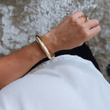 Pulseira Olivia Gold dourada tipo bracelete larga, acabamento polido, fecho discreto.