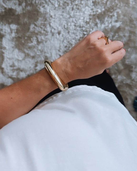 Pulseira Olivia Gold dourada tipo bracelete larga, acabamento polido, fecho discreto.